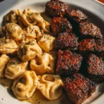 Garlic Butter Steak Bites served with creamy Alfredo tortellini on a plate