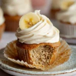Delicious banana cupcakes with cinnamon cream cheese frosting on a white plate.