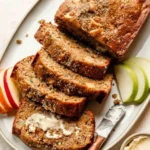 Slice of homemade apple zucchini bread on a wooden table