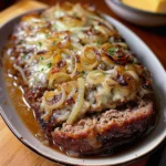 Crockpot French Onion Beef Meatloaf garnished with herbs on a plate.
